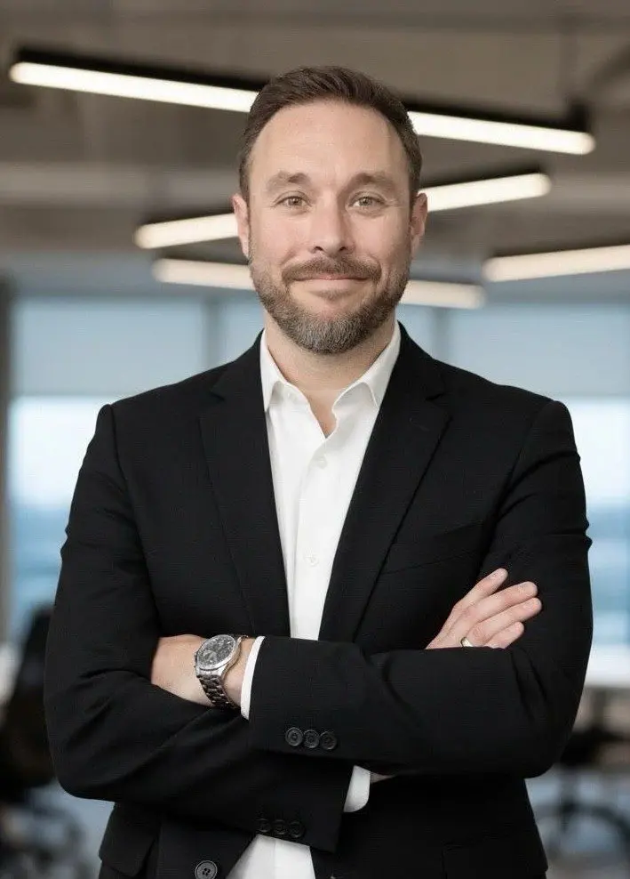Man in suit with crossed arms, smiling.