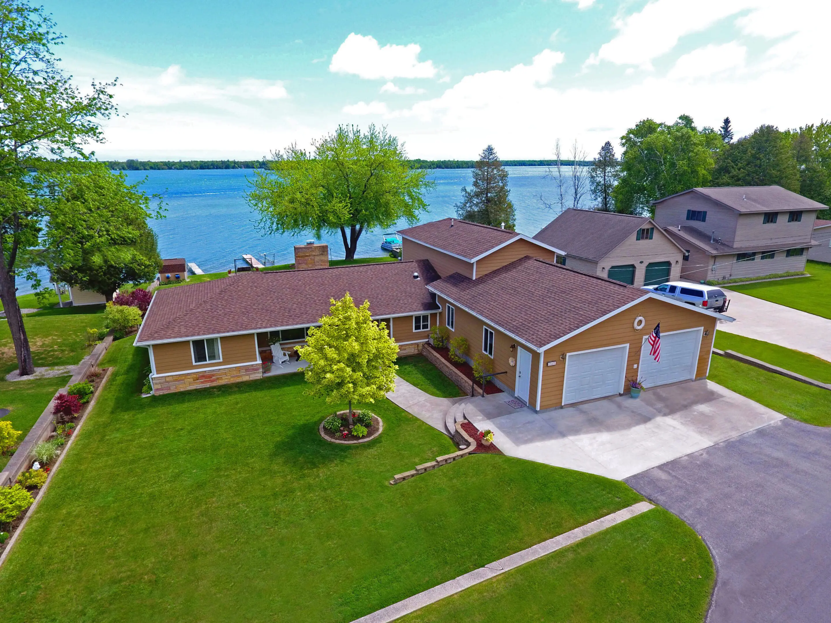 Lakeside house with garage and green lawn.