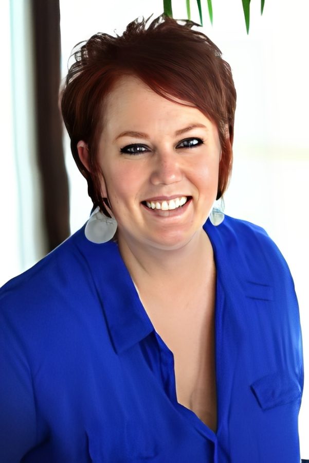 Smiling woman with short red hair and blue blouse.