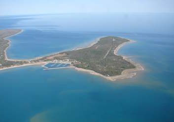 Aerial view of a small, green island surrounded by clear blue water.