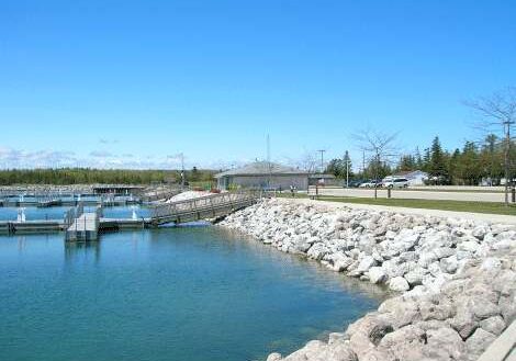 Calm water body with a rocky embankment under a clear blue sky.