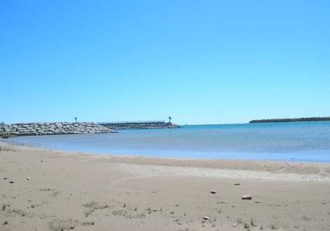 Calm beach with gentle waves and clear blue sky.