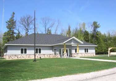 Modern single-story building with a stone facade and gray roof.