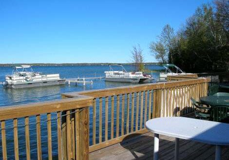 Sunny waterfront view with boats docked and wooden railing.