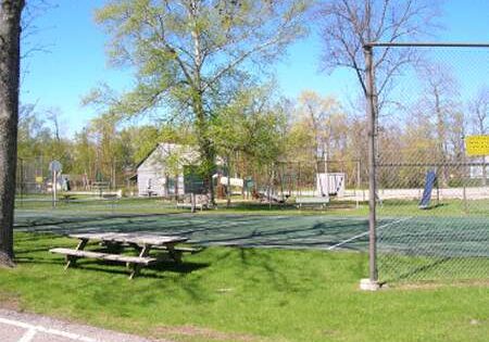 A quiet outdoor park with picnic tables and basketball courts on a sunny day.